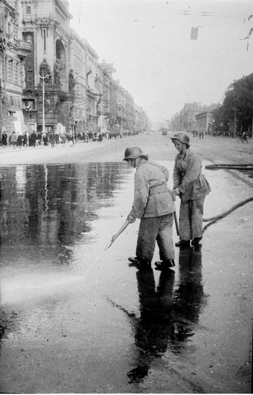 Пожарные смывают с асфальта кровь убитых в результате немецкого артобстрела